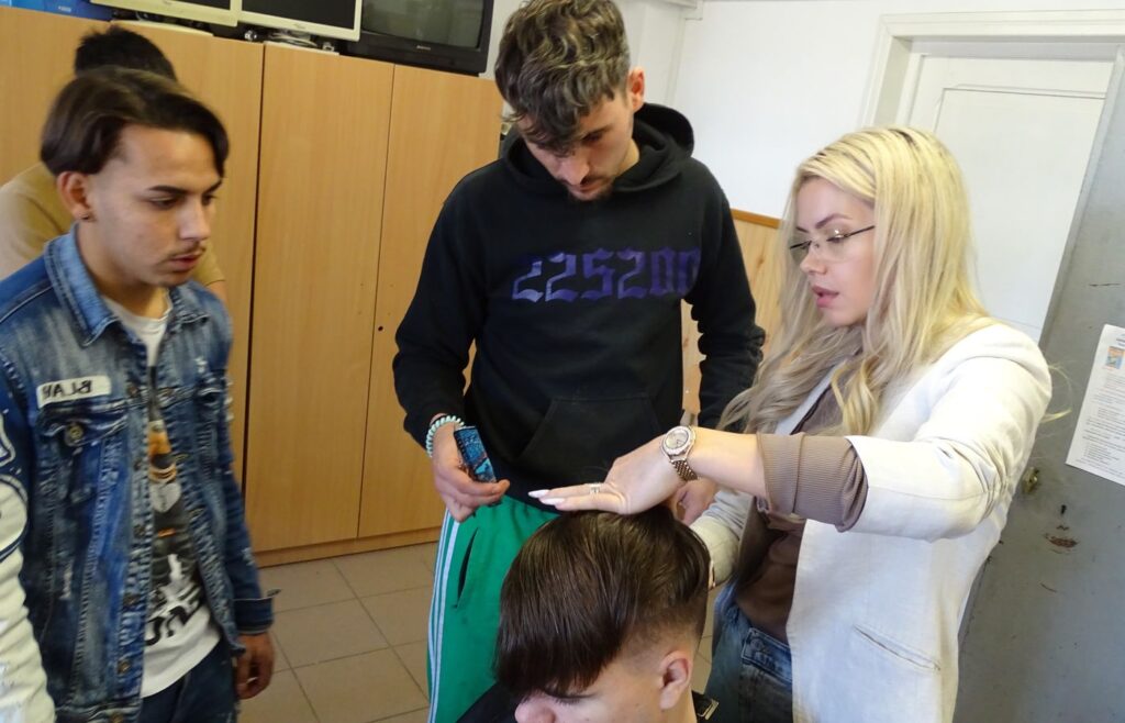 Trainerul corectează pe loc tunsoarea unui cursant